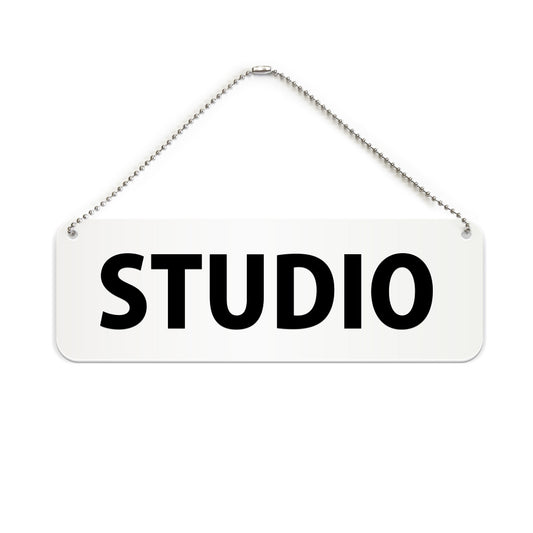 STUDIO と書かれた横長プレート看板（白いアクリル板・黒文字）